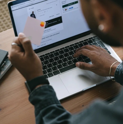 A shopper holding a payment card while checking out on a laptop